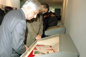 Des invités devant les documents exposés sous vitrine